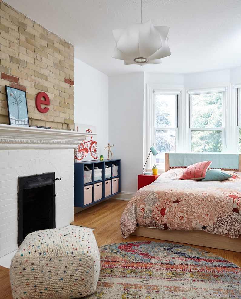 Bild på ett stort minimalistiskt sovrum, med vita väggar, ljust trägolv, en standard öppen spis, en spiselkrans i tegelsten och beiget golv