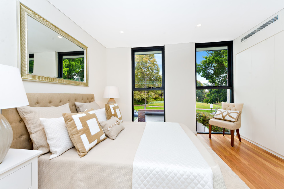 Cette image montre une chambre traditionnelle avec un mur blanc et parquet clair.