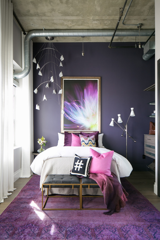 Aménagement d'une chambre d'amis industrielle de taille moyenne avec un mur violet, un sol en bois brun et un sol gris.