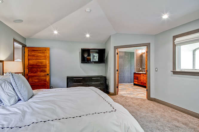 Modelo de dormitorio principal minimalista grande con paredes azules, moqueta, todas las chimeneas y marco de chimenea de piedra