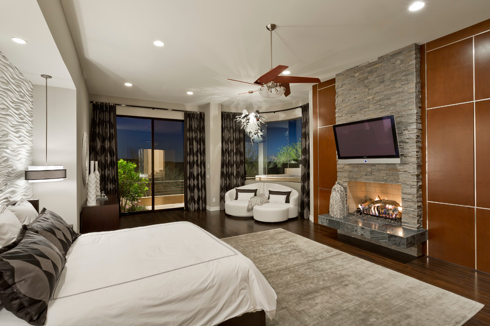 На фото: огромная хозяйская спальня в современном стиле с серыми стенами, стандартным камином и фасадом камина из камня с