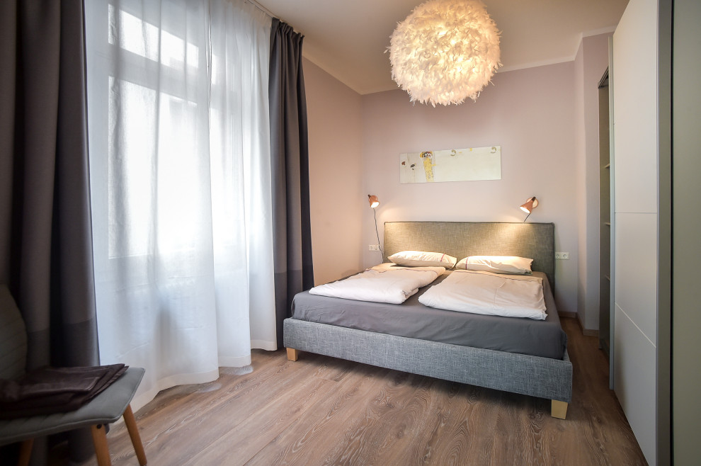 Ispirazione per una camera da letto minimalista di medie dimensioni con pavimento in laminato e pavimento marrone