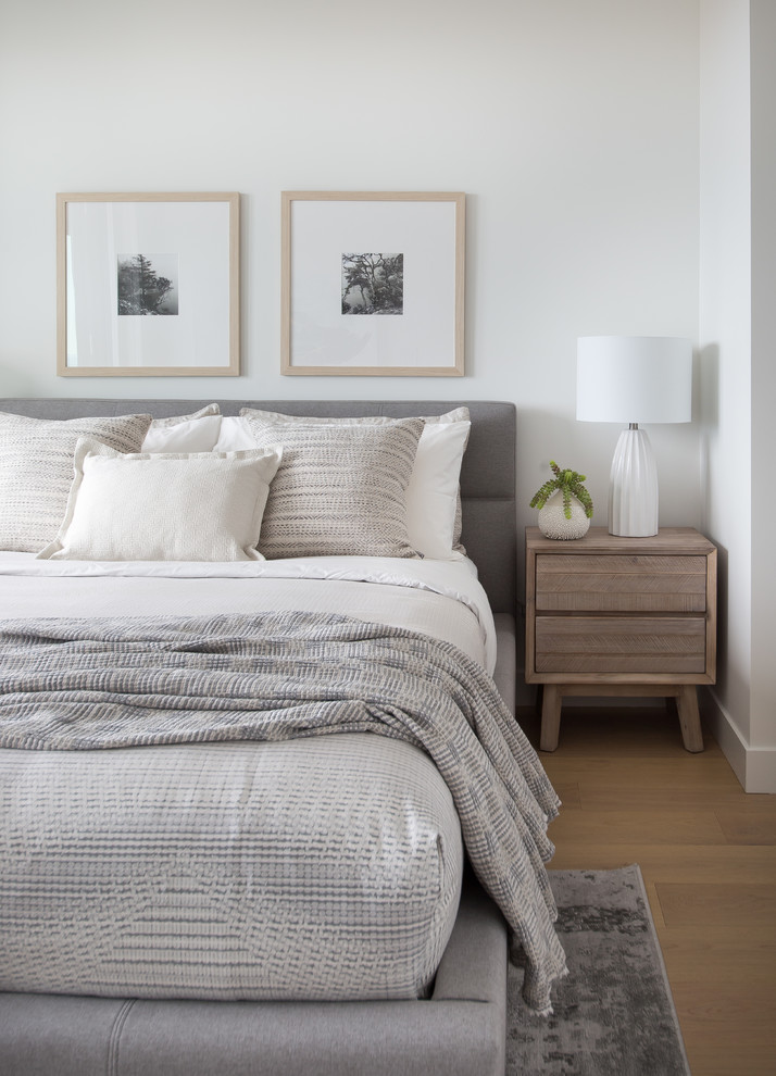 Modelo de dormitorio de estilo de casa de campo con paredes blancas, suelo de madera clara y suelo beige