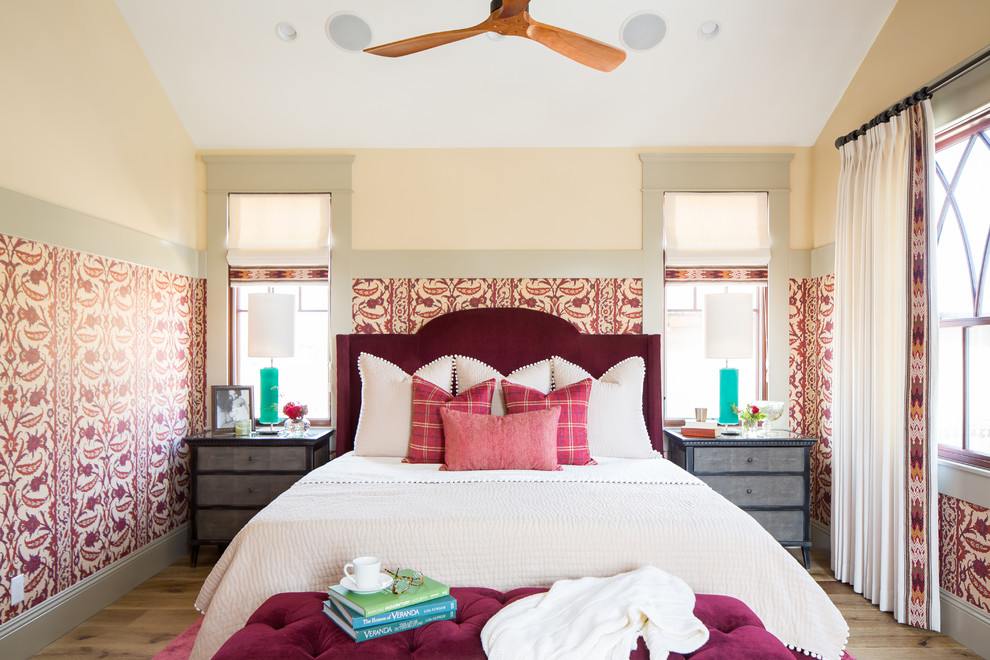 Example of an eclectic medium tone wood floor and brown floor bedroom design in San Diego with beige walls