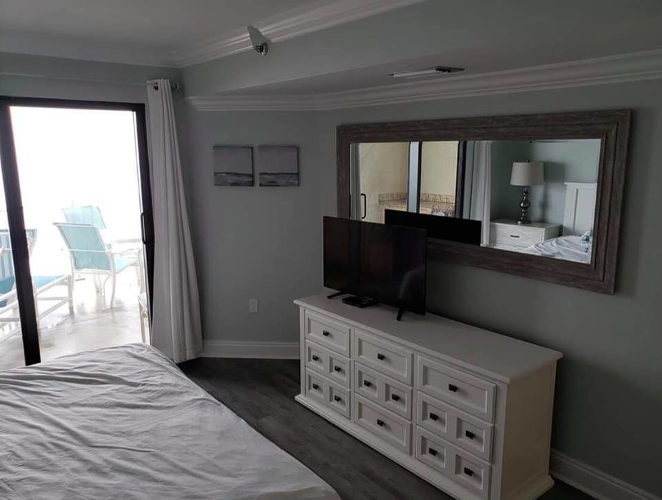 マイアミにある広いビーチスタイルのおしゃれな主寝室 (グレーの壁、濃色無垢フローリング、暖炉なし、茶色い床) のレイアウト