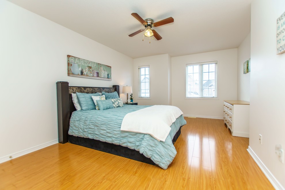Large transitional guest light wood floor bedroom photo in Toronto with beige walls