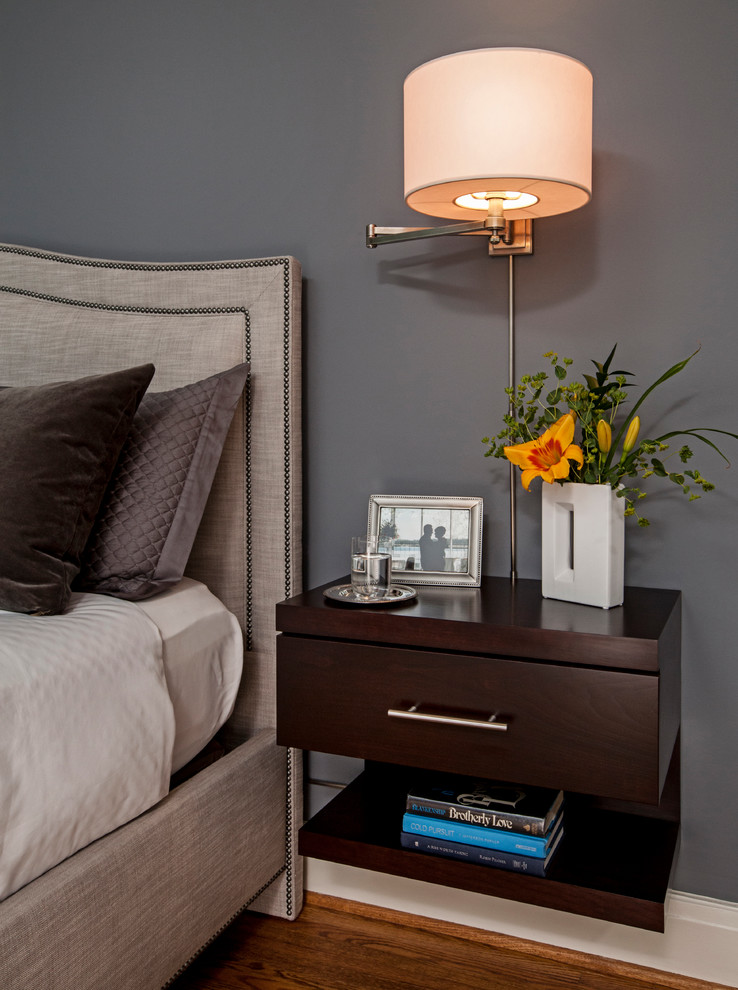 Cette image montre une chambre parentale minimaliste avec un mur gris et un sol en bois brun.
