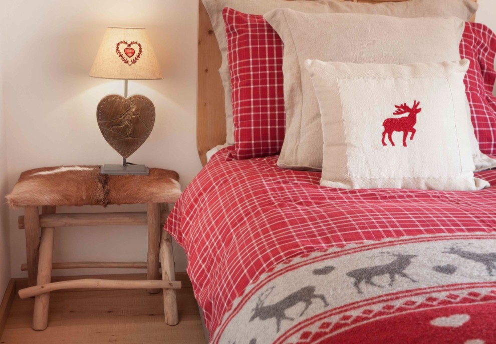 Idée de décoration pour une chambre d'amis chalet de taille moyenne avec un mur blanc, parquet clair et un sol beige.