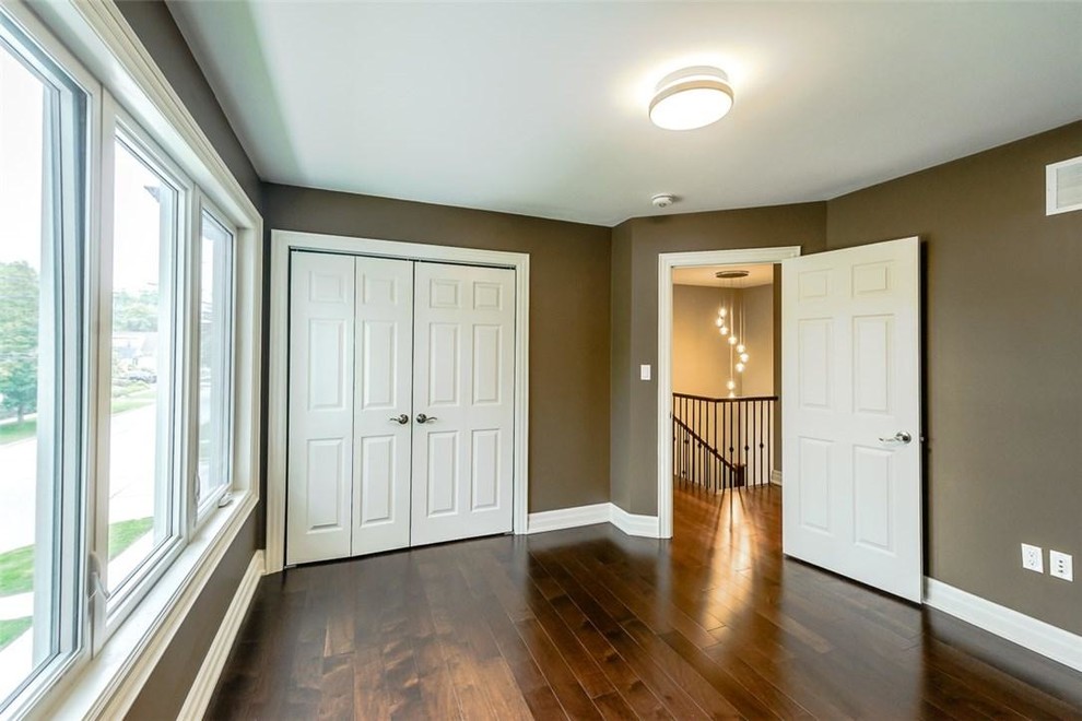 Cette photo montre une chambre d'amis moderne de taille moyenne avec un mur beige, un sol en bois brun, aucune cheminée et un sol marron.