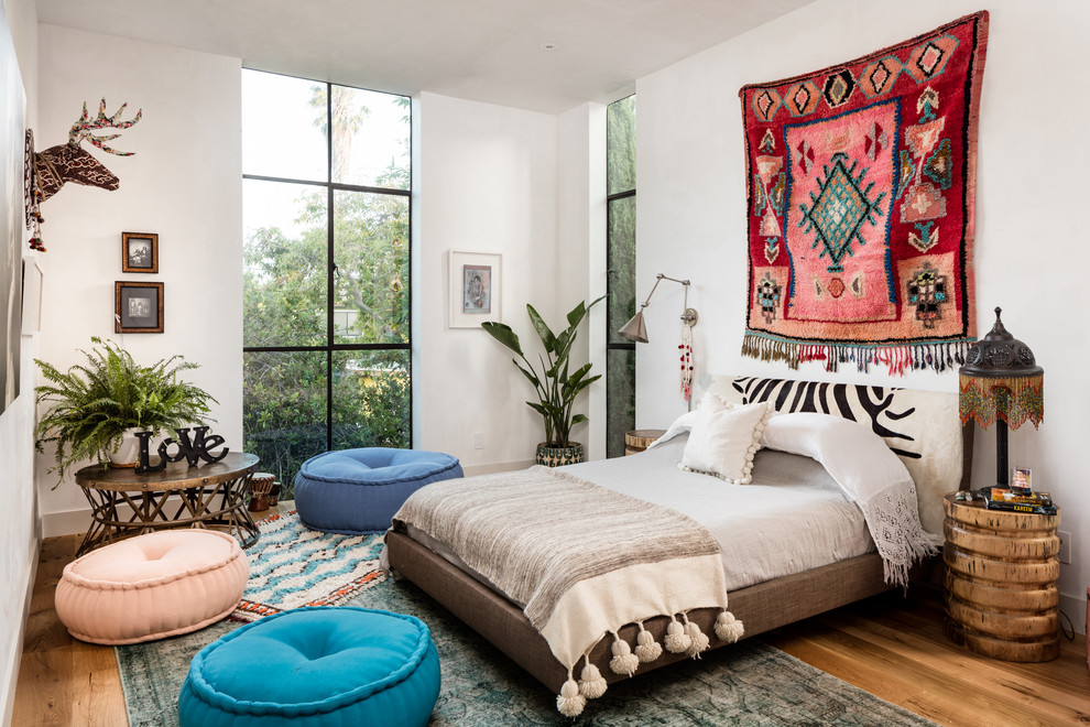 Eclectic master bedroom in New York with white walls, medium hardwood flooring and no fireplace.