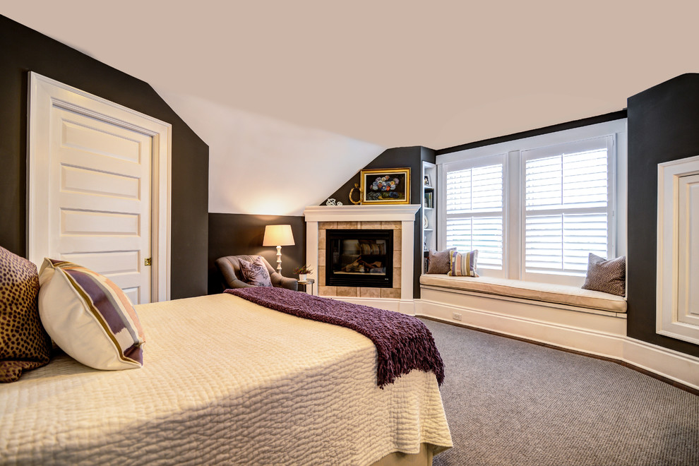 Modelo de dormitorio principal de estilo americano pequeño con paredes grises, suelo de madera oscura, chimenea de esquina y marco de chimenea de baldosas y/o azulejos