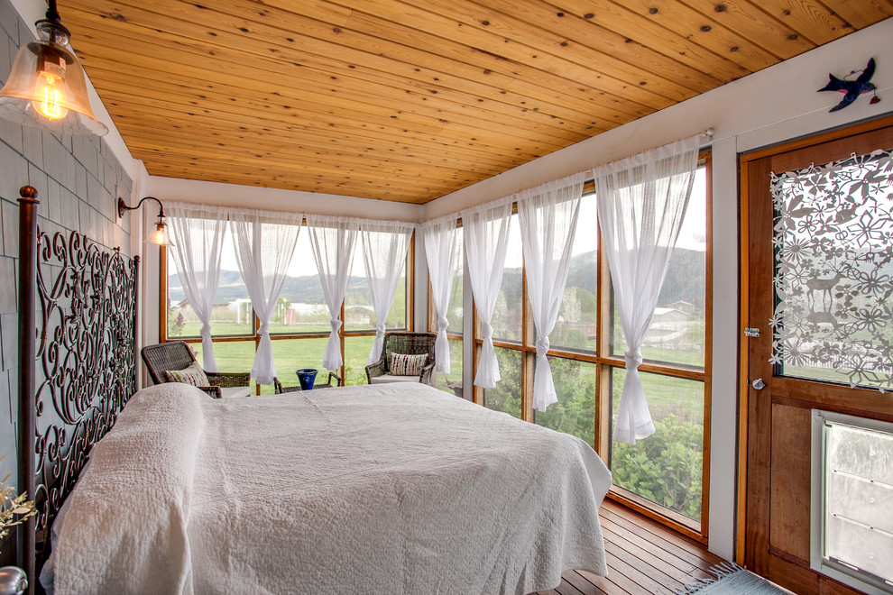 Modelo de habitación de invitados de estilo de casa de campo sin chimenea con paredes blancas y suelo de madera en tonos medios