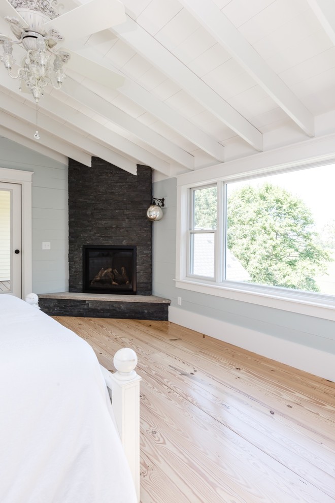 Inspiration for a large cottage master light wood floor bedroom remodel in Other with blue walls, a corner fireplace and a stone fireplace