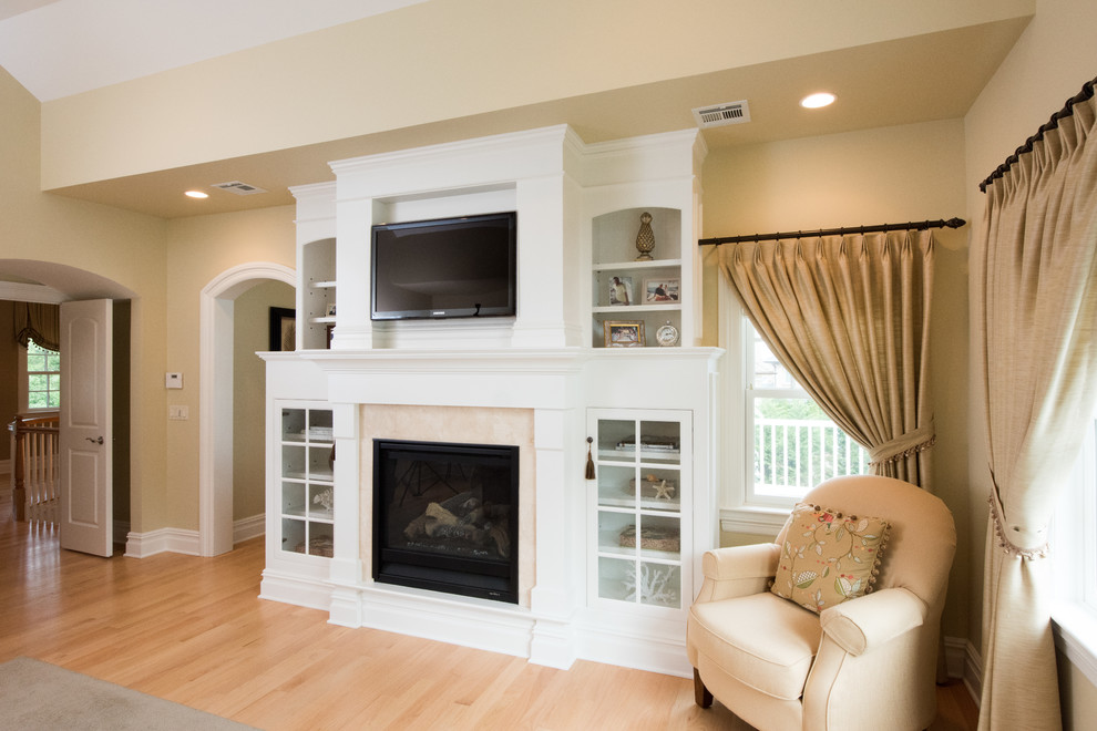 Cette image montre une grande chambre parentale traditionnelle avec un mur beige, parquet clair, une cheminée standard et un manteau de cheminée en bois.