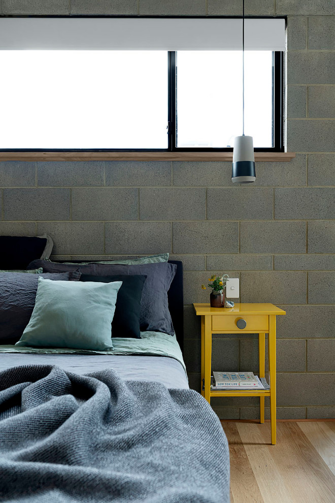 Idee per una camera matrimoniale minimalista con pareti grigie, parquet chiaro e pareti in mattoni