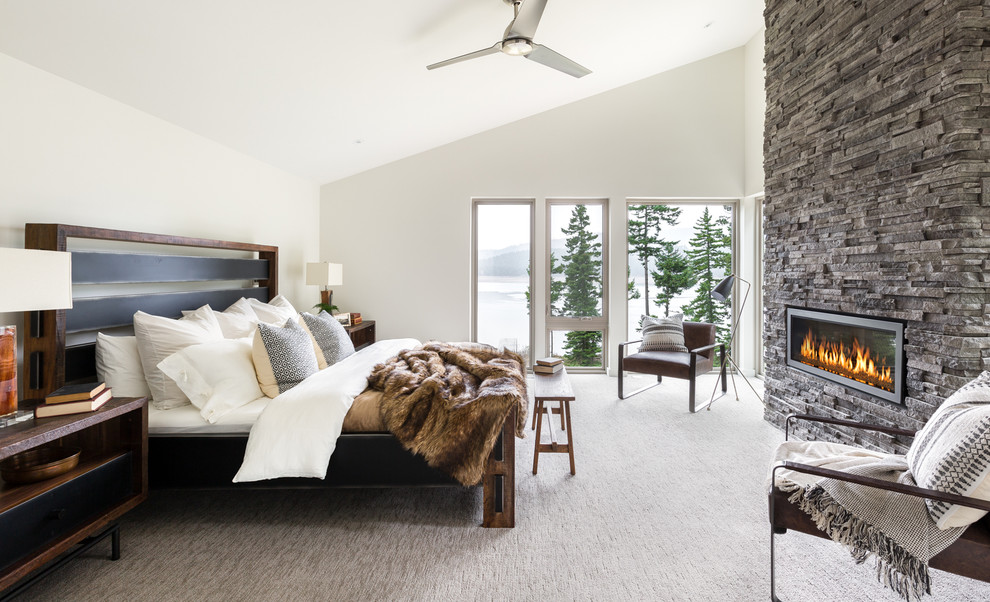Diseño de dormitorio contemporáneo con paredes blancas, moqueta, chimenea lineal y marco de chimenea de piedra