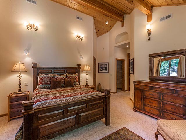 Mid-sized mountain style master carpeted bedroom photo in Sacramento with beige walls, a corner fireplace and a stone fireplace