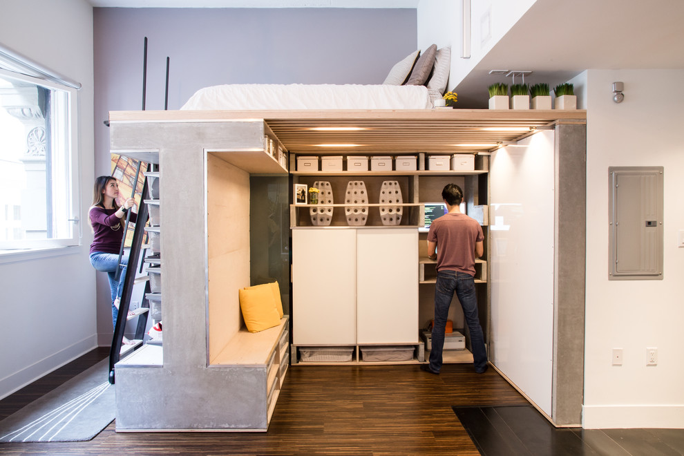 Exemple d'une petite chambre mansardée ou avec mezzanine industrielle avec un mur gris, un sol en bois brun et aucune cheminée.