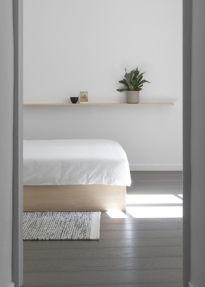 Cette photo montre une chambre parentale scandinave de taille moyenne avec un mur blanc, un sol en bois brun et un sol gris.