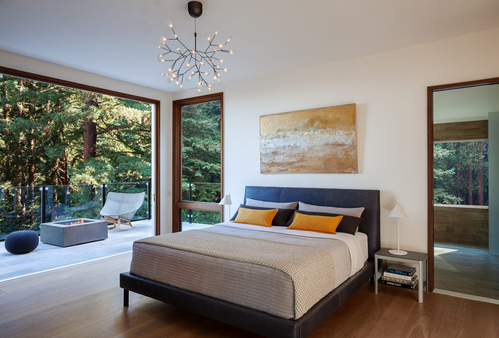 Ejemplo de dormitorio actual con paredes blancas, suelo de madera en tonos medios y suelo marrón