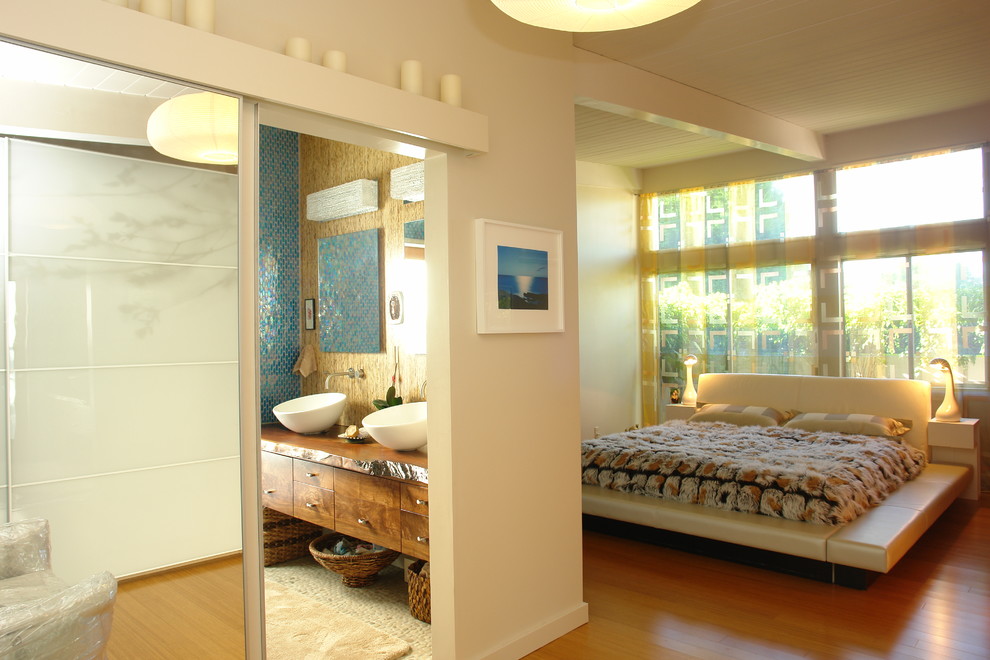 Ejemplo de dormitorio principal tropical grande sin chimenea con paredes beige y suelo de madera en tonos medios