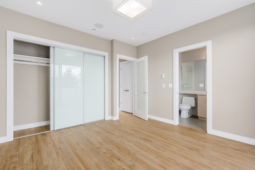 Imagen de dormitorio principal minimalista pequeño sin chimenea con paredes beige y suelo de madera clara