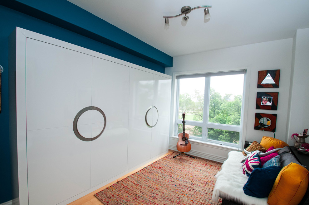 Ejemplo de habitación de invitados contemporánea grande sin chimenea con paredes azules, suelo de madera clara y suelo marrón