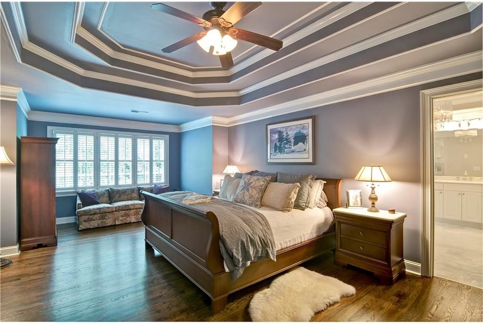 Cette image montre une grande chambre traditionnelle avec un mur bleu, un sol en bois brun et un sol marron.