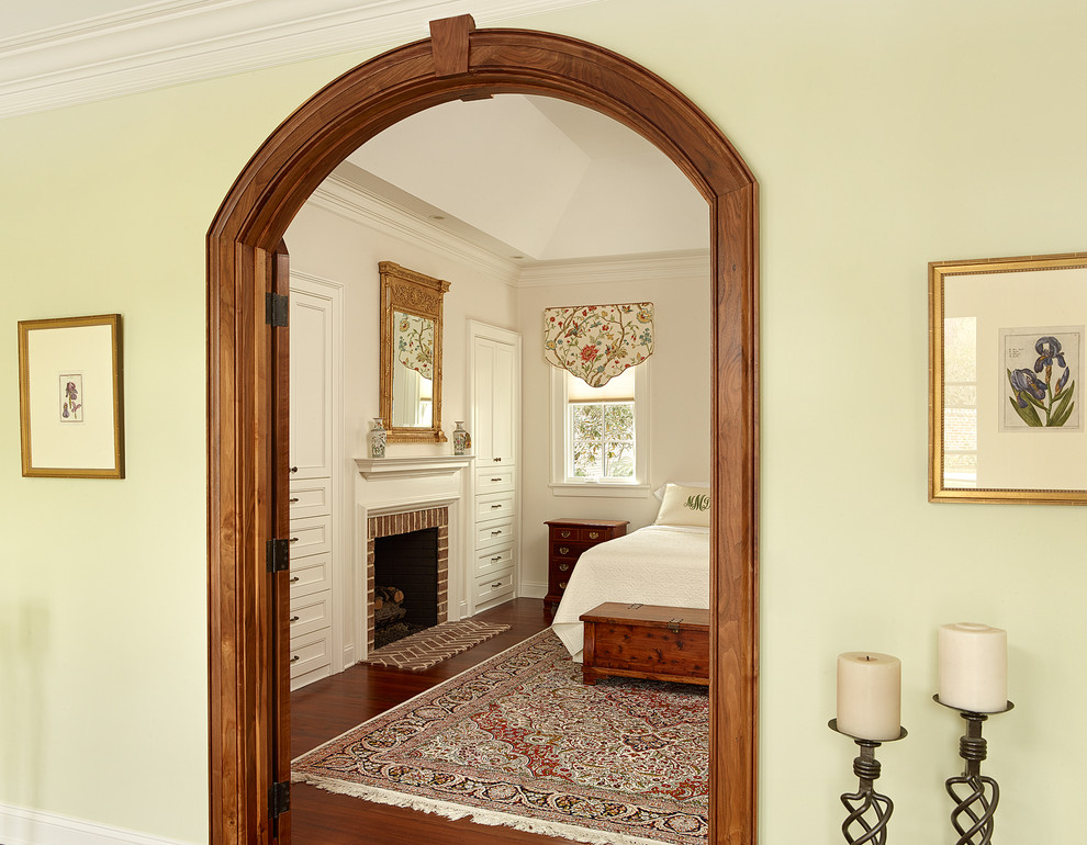 Klassisches Hauptschlafzimmer mit grüner Wandfarbe, braunem Holzboden, Kamin und Kaminumrandung aus Backstein in Charleston