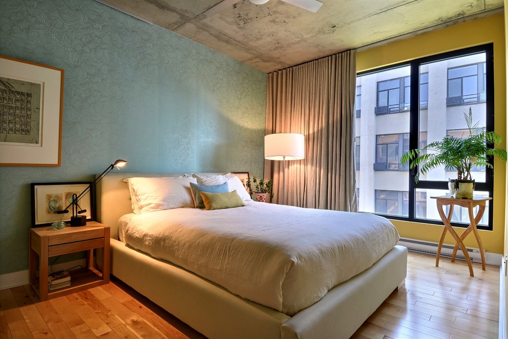 Modelo de dormitorio actual con paredes amarillas y suelo de madera en tonos medios