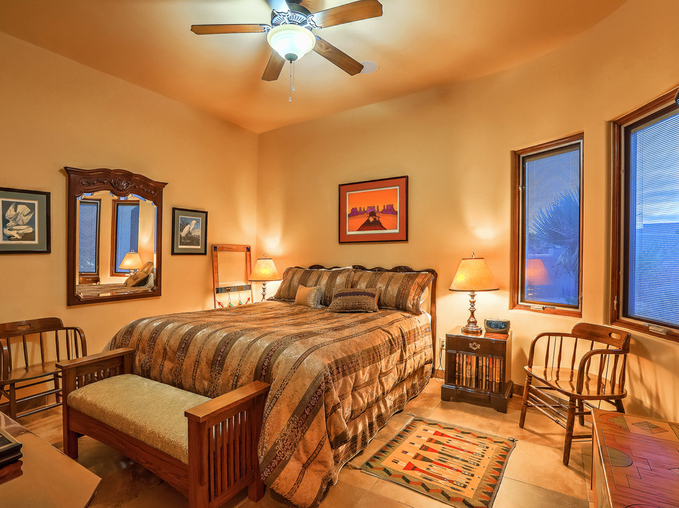 Design ideas for a medium sized master bedroom in Albuquerque with yellow walls, slate flooring, a standard fireplace, a plastered fireplace surround and multi-coloured floors.