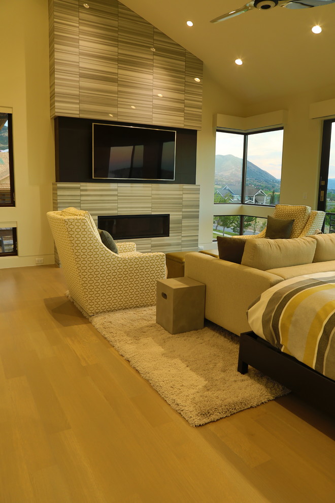 Modelo de dormitorio principal clásico renovado grande con paredes beige, suelo de madera clara, chimenea lineal y marco de chimenea de baldosas y/o azulejos