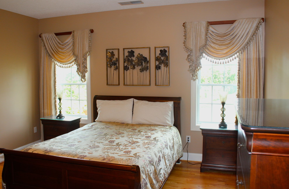 Diseño de dormitorio principal tradicional de tamaño medio sin chimenea con paredes beige y suelo de madera clara