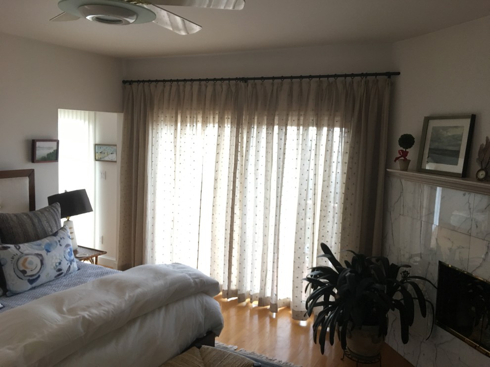 Imagen de dormitorio principal clásico grande con paredes blancas, suelo de madera clara, chimenea de esquina y marco de chimenea de baldosas y/o azulejos