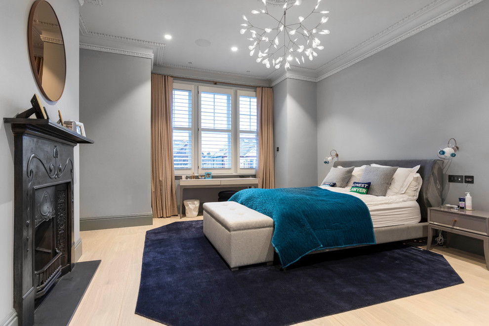 ロンドンにあるトランジショナルスタイルのおしゃれな寝室 (グレーの壁、淡色無垢フローリング、標準型暖炉、ベージュの床) のインテリア