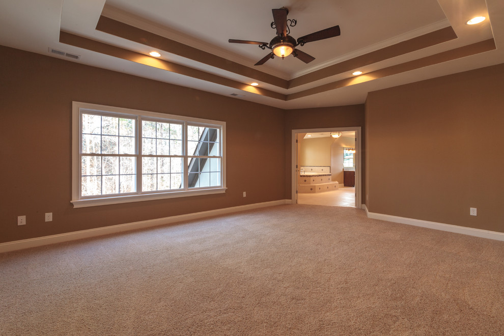 Example of a large classic master carpeted bedroom design in Charlotte with beige walls