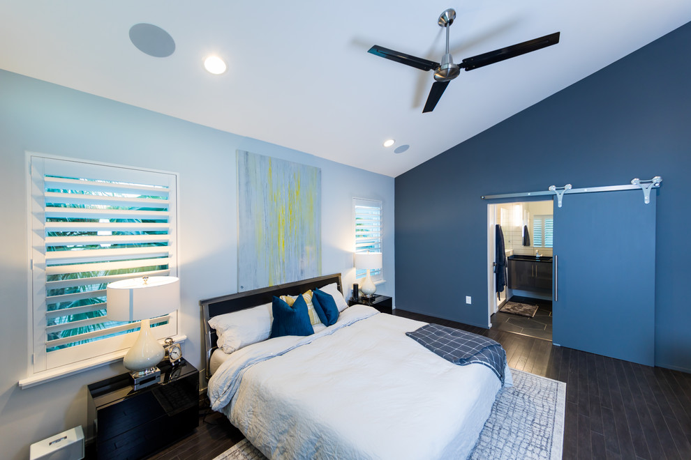 Cette image montre une chambre parentale design de taille moyenne avec parquet foncé, un sol marron et un mur bleu.