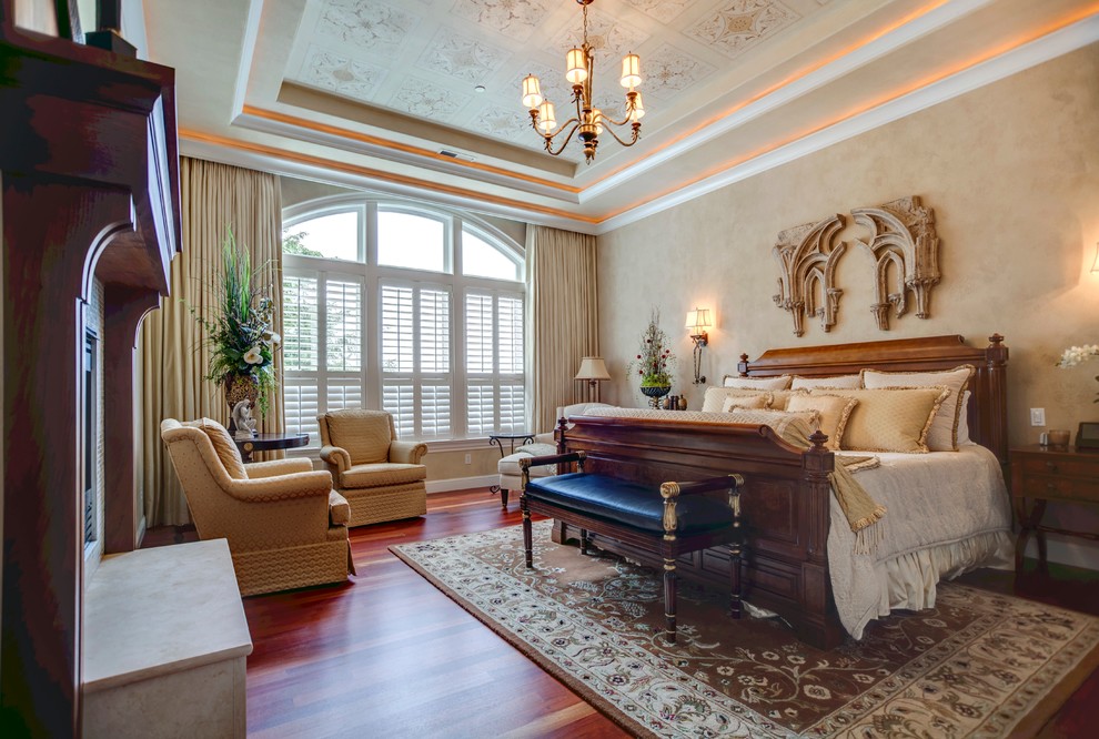 Foto di una camera da letto tradizionale con pareti beige, pavimento in legno massello medio e camino classico