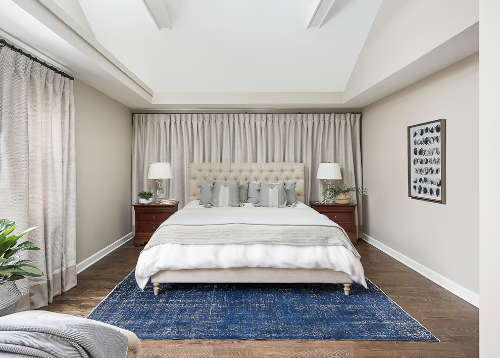 Modelo de dormitorio principal clásico renovado grande con paredes beige, suelo de madera en tonos medios y suelo marrón