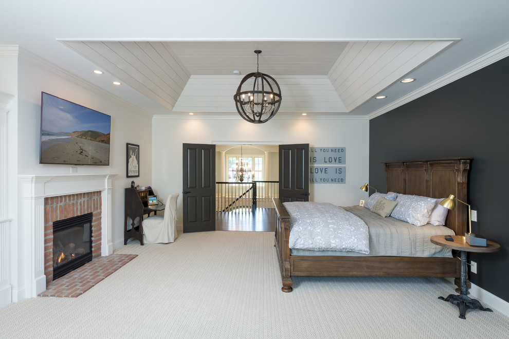 На фото: большая хозяйская спальня в классическом стиле с белыми стенами, ковровым покрытием, стандартным камином, фасадом камина из кирпича и серым полом