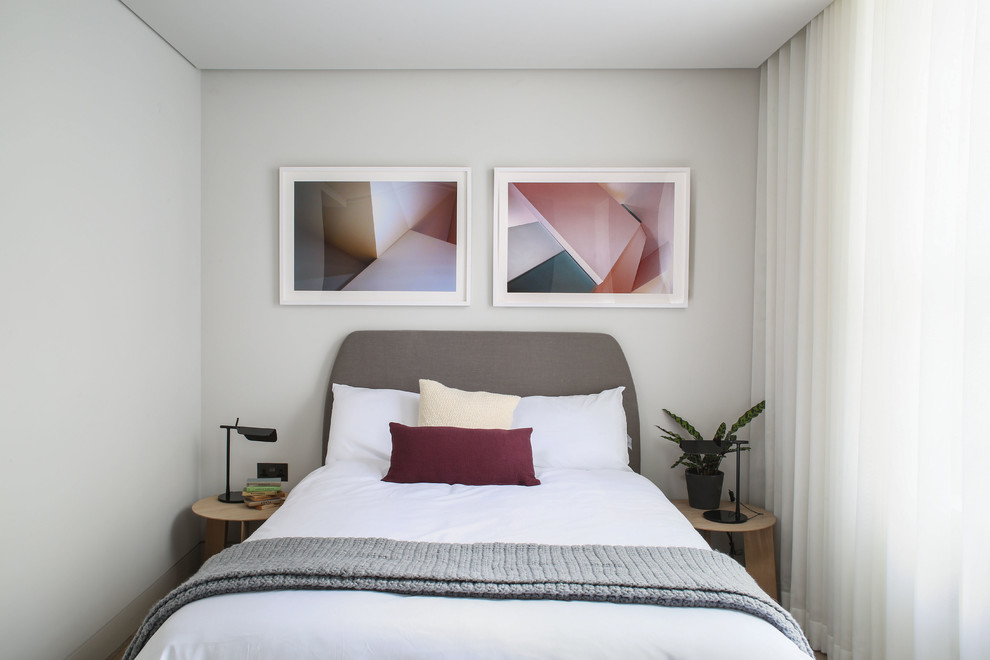 Imagen de habitación de invitados actual pequeña sin chimenea con paredes blancas y suelo de madera clara