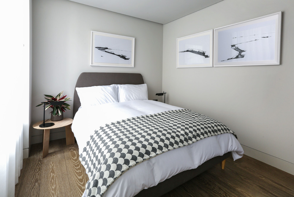 Ejemplo de habitación de invitados actual pequeña sin chimenea con paredes beige y suelo de madera clara