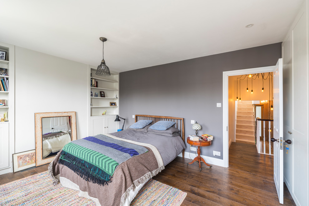 Example of a mid-sized eclectic master dark wood floor and brown floor bedroom design in London with gray walls