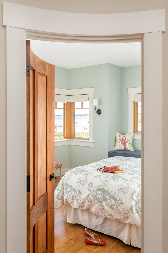 Aménagement d'une chambre parentale bord de mer de taille moyenne avec un mur bleu, parquet clair, aucune cheminée et un sol marron.