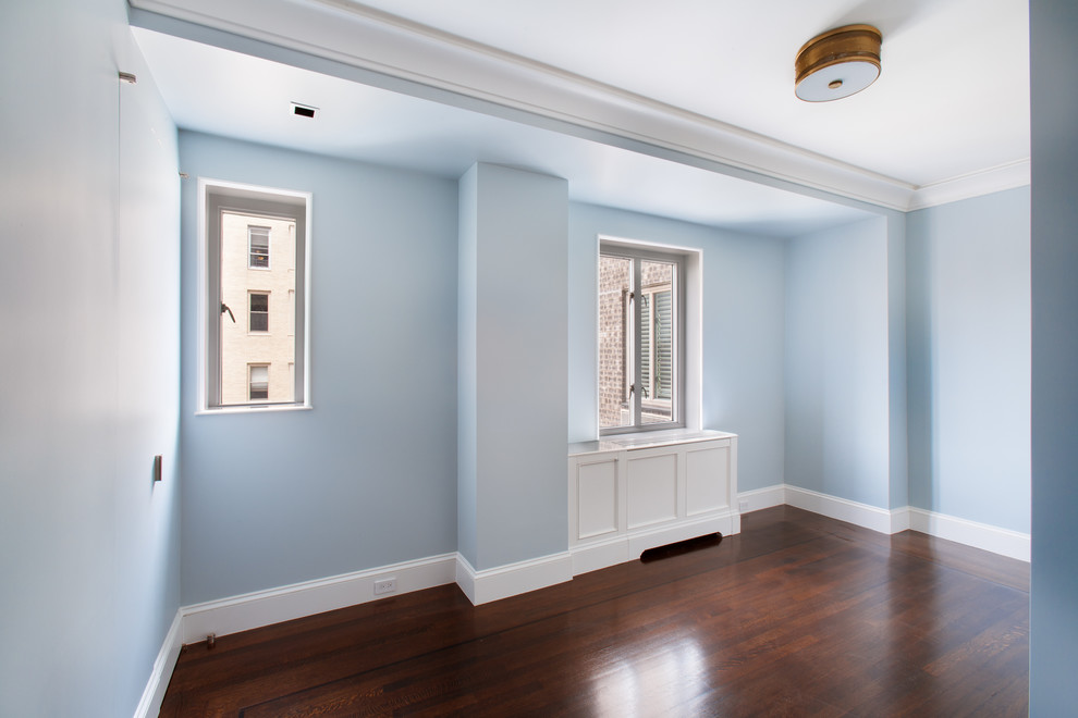 Cette image montre une chambre d'amis traditionnelle de taille moyenne avec un mur bleu et parquet foncé.