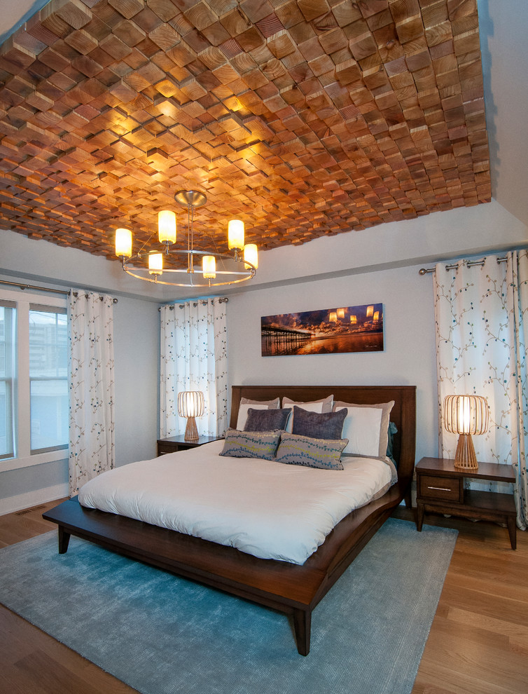 Esempio di una camera matrimoniale design di medie dimensioni con pareti blu, pavimento in legno massello medio e cornice del camino piastrellata