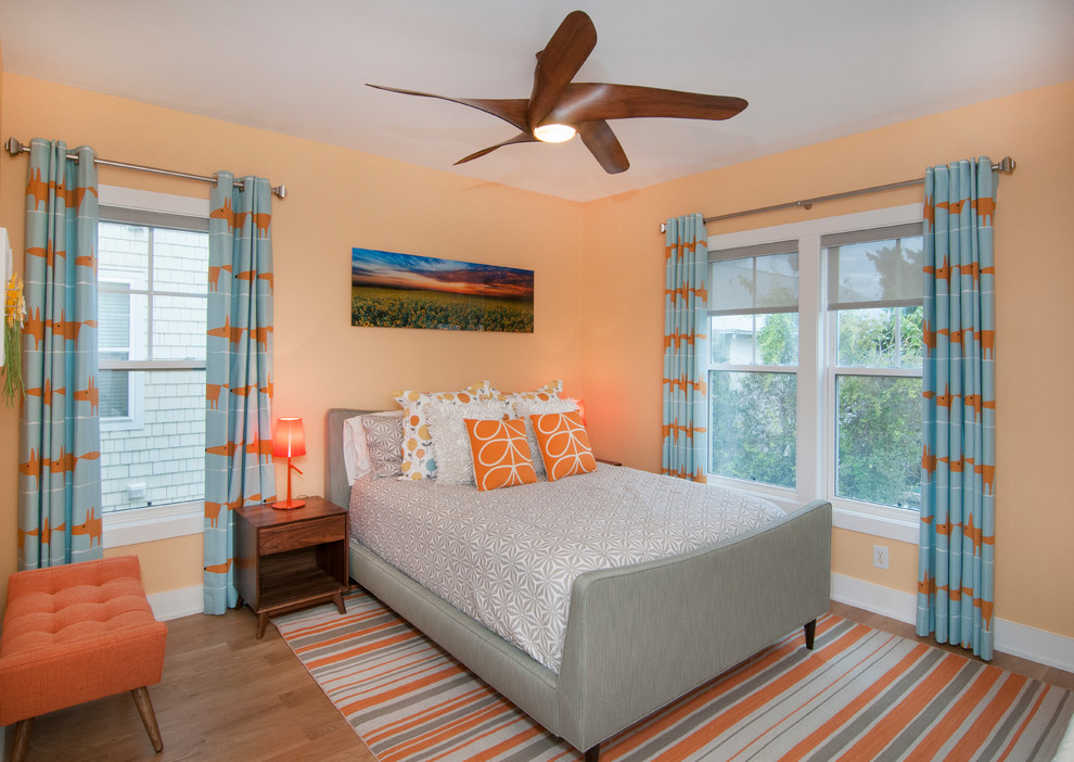 Cette image montre une chambre d'amis design de taille moyenne avec un mur orange et un sol en bois brun.