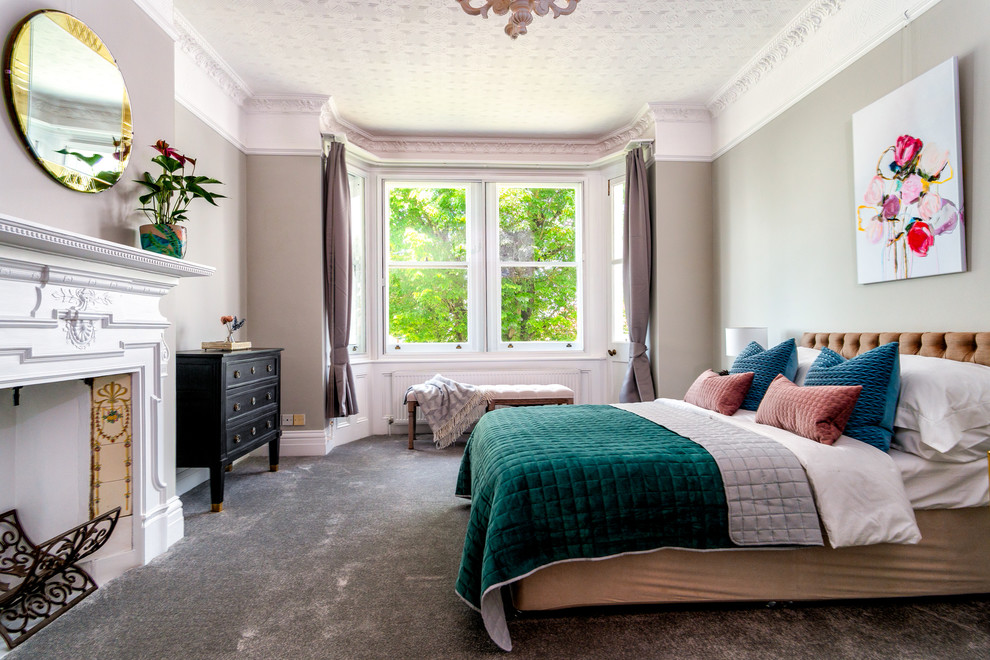 Großes Modernes Gästezimmer mit grauer Wandfarbe, Teppichboden, Kamin, Kaminumrandung aus Holz und grauem Boden in Sussex