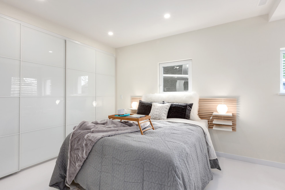 Modelo de dormitorio principal contemporáneo de tamaño medio sin chimenea con paredes blancas, suelo de cemento y suelo blanco