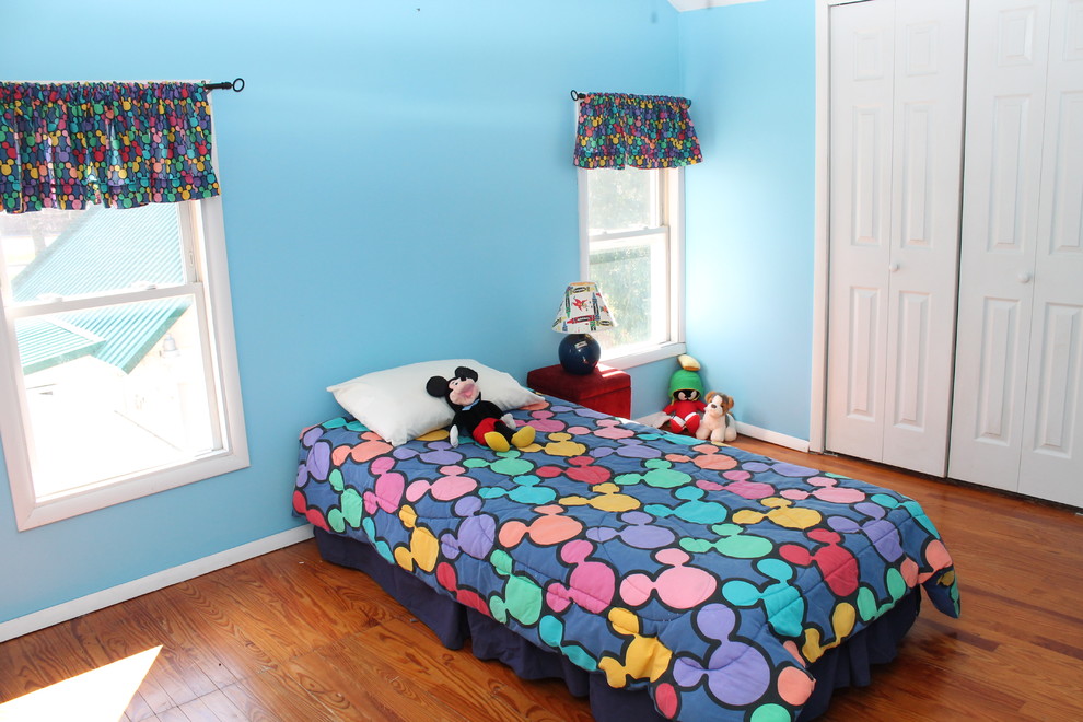 Mittelgroßes Schlafzimmer mit blauer Wandfarbe und braunem Holzboden in New York